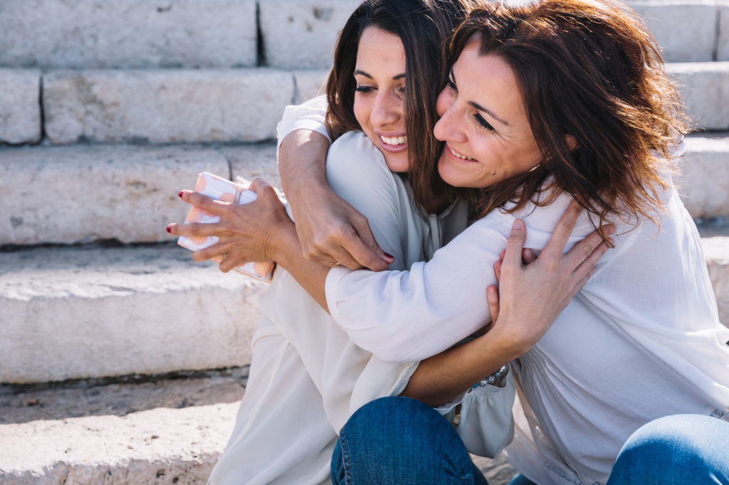 mother-with-gift-hugging-woman