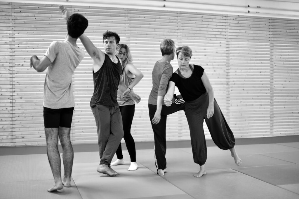 contact-improvisation-3684693 fekete-fehér kép melyen emberek csoportja laza ruhában ráncol, érintkezik személyiségfejlesztés csoportos óra keretében